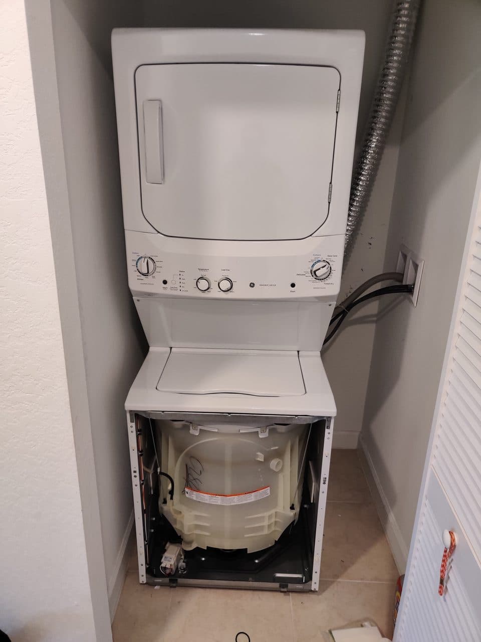 Laundry center with the washer panel off: GE laundry center, model GUD27ESSM1WW (washer repair in Greenacres, FL, September 2026)